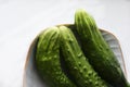 Three green cucumbers on a plate on a white background Royalty Free Stock Photo