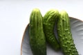 Three green cucumbers on a plate on a white background Royalty Free Stock Photo