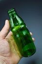 Three green empty glass soda bottles and hand, isolated on gray background Royalty Free Stock Photo