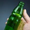 Three green empty glass soda bottles and hand, isolated on gray background Royalty Free Stock Photo