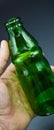 Three green empty glass soda bottles and hand, isolated on gray background Royalty Free Stock Photo