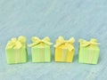 Three green, and one yellow square gift box on a blue-green-grey watercolor textured background, copy space. Royalty Free Stock Photo