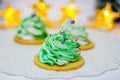 Three green herringbone-shaped marshmallows on a white openwork napkin. The background consists of a garland in the form of