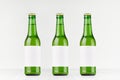 Three green longneck beer bottles 330ml with blank white label on white wooden board, mock up. Royalty Free Stock Photo