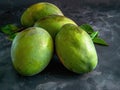 Three green mangoes on a black surface Royalty Free Stock Photo