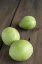 Three green walnuts on a wooden table. Unpeeled nuts. On a wooden background there are three walnuts in a green shell. Royalty Free Stock Photo