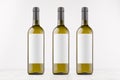 Three green wine bottles with blank white labels on white wooden board, mock up. Royalty Free Stock Photo
