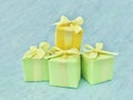 Three green, and one yellow square gift boxes stacked on a blue-green-gray watercolor textured background. Royalty Free Stock Photo
