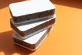 Three grey kitchen sponges on the orange background Royalty Free Stock Photo