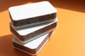 Three grey kitchen sponges on the orange background Royalty Free Stock Photo