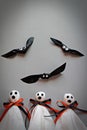 Three halloween ghosts and orange ribbon and three bats on gray background Royalty Free Stock Photo