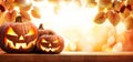 Three halloween pumpkin lanterns with a scary evil faces and eyes on a wood table