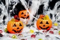 Three halloween pumpkins with candies inside, cobweb, candies everywhere and spiders