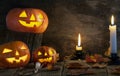 Three Halloween pumpkins head jack o lantern on wooden table background