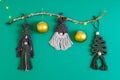 Three knitted Christmas tree toys with a branch, a garland and two Christmas balls on a green background. Royalty Free Stock Photo