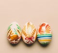 Three handmade Easter eggs on creamy background