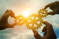 Three hands of businessmen assemble gears into a puzzle in a single whole against the backdrop of the sunset, business concept ide Royalty Free Stock Photo