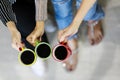 Three hands of woman hold 3 ceramic coffee cups and touch them together in the symbol of friendship, unity and teamwork. Taken Royalty Free Stock Photo