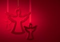 Three hanging glass silhouettes of angel against burgundy red background