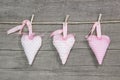 Three hanging hearts on a wooden board.
