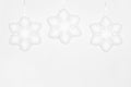 Three hanging white snowflakes on white wall. Copy space. Simple winter background