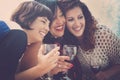 Three happy and beautiful females friends have fun together at home drinking some red wine and enjoying the leisure and tie