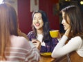 Three young asian women chatting talking in coffee shop