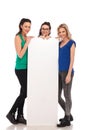 Three happy casual women presenting a big blank board Royalty Free Stock Photo