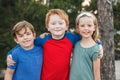 Three happy Caucasian little children kids boys and girl hugging together outdoor in park. Group of smiling friends. Best friends Royalty Free Stock Photo