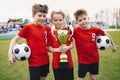 Three Happy Cheerful Kids of Sports Soccer Team. Boys Football Players Holding Trophy at the Stadium Royalty Free Stock Photo