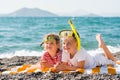 Three happy children on beach with colorful face masks and snorkels, sea in background. Summer vacation Royalty Free Stock Photo