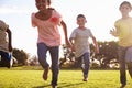 Three happy children running barefoot in a field in Summer Royalty Free Stock Photo