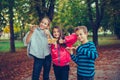 Three happy children talking and eating pizza outdoors, showing thumb up Royalty Free Stock Photo