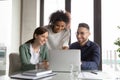 Three happy diverse colleagues working on project together, using laptop Royalty Free Stock Photo