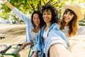 Three happy diverse girls having fun enjoying bicycle ride on city park Royalty Free Stock Photo