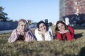 Three happy female girls lying on the grass in a public park at the city Royalty Free Stock Photo