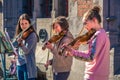 Three happy female teen violinists play for donation