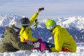 Three happy friends snowboarders and skier are having lunchtime and make selfie on a smartphone on a ski slope in sunny day in the Royalty Free Stock Photo