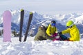 Three happy friends snowboarders and skier are having lunchtime on ski slope in sunny day in the mountains Royalty Free Stock Photo