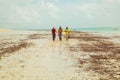 Three happy kenyan fishermen walk along the ocean shore talking and laughing