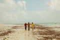 Three happy kenyan fishermen walk along the ocean shore talking and laughing