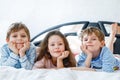 Three happy kids in pajamas celebrating pajama party. Preschool and school boys and girl in nightwear having fun Royalty Free Stock Photo