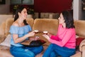 Three happy latin friends women talking and drinking coffee and tea sitting on a couch at home in Mexico city Royalty Free Stock Photo