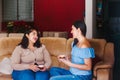 Three happy latin friends women talking and drinking coffee and tea sitting on a couch at home in Mexico city Royalty Free Stock Photo