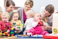 Three happy mothers watching their babies playing with safe toys Royalty Free Stock Photo