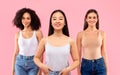 Three happy multiethnic women posing over pink studio background and smiling to camera, studio shot Royalty Free Stock Photo