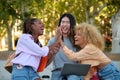 Three happy multiracial friends high five and laughing at a park.