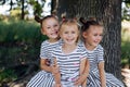 Three happy sisters in dresses smile and hug in the park. Happy childhood. The twins Royalty Free Stock Photo