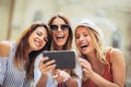 Three happy smiling female friends sharing a tablet computer as they stand close together looking at the screen Royalty Free Stock Photo