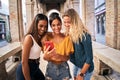 Three happy smiling female friends sharing a tablet computer as they stand close together looking at the Royalty Free Stock Photo